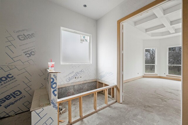 interior space with beamed ceiling, coffered ceiling, and concrete floors