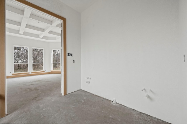 empty room with coffered ceiling, beam ceiling, and concrete floors