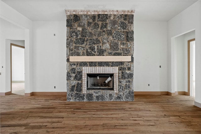 unfurnished living room featuring hardwood / wood-style flooring and a stone fireplace