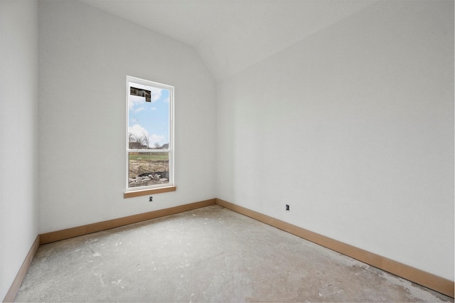 spare room featuring lofted ceiling and concrete floors