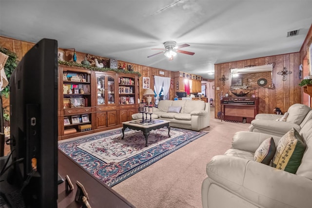 living room featuring wooden walls, light colored carpet, and ceiling fan