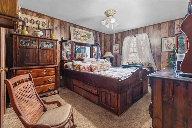 bedroom with light colored carpet and wood walls