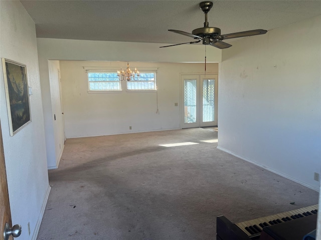 carpeted empty room featuring an inviting chandelier and french doors