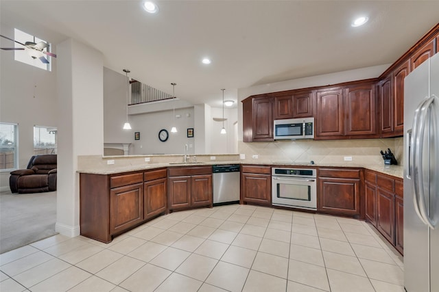 kitchen featuring light tile patterned floors, appliances with stainless steel finishes, backsplash, decorative light fixtures, and kitchen peninsula