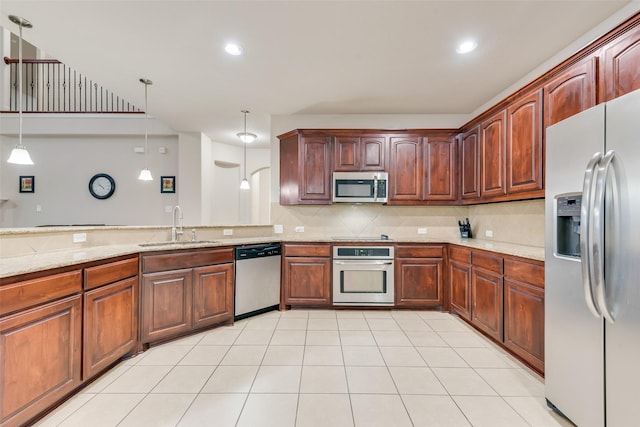 kitchen with sink, decorative light fixtures, appliances with stainless steel finishes, light stone countertops, and backsplash