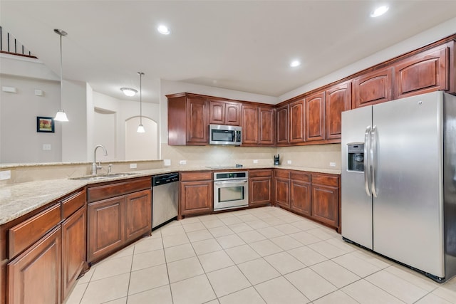 kitchen with sink, light stone counters, tasteful backsplash, hanging light fixtures, and appliances with stainless steel finishes