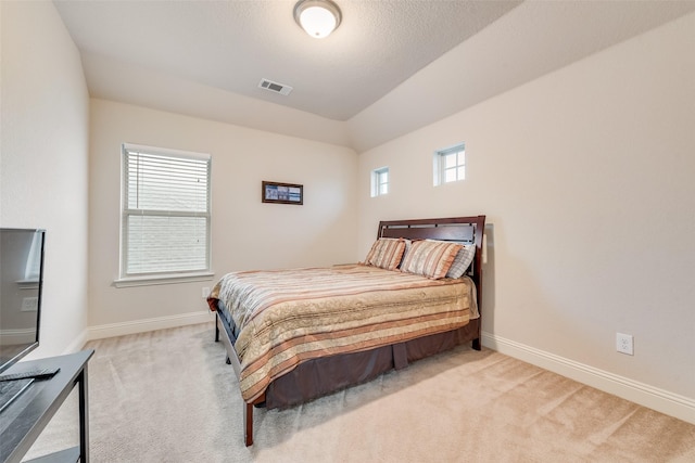 bedroom with multiple windows, vaulted ceiling, and light carpet