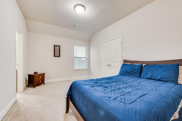 bedroom with carpet flooring, vaulted ceiling, and a textured ceiling