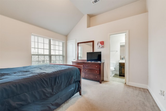 bedroom featuring lofted ceiling, ensuite bathroom, and light carpet