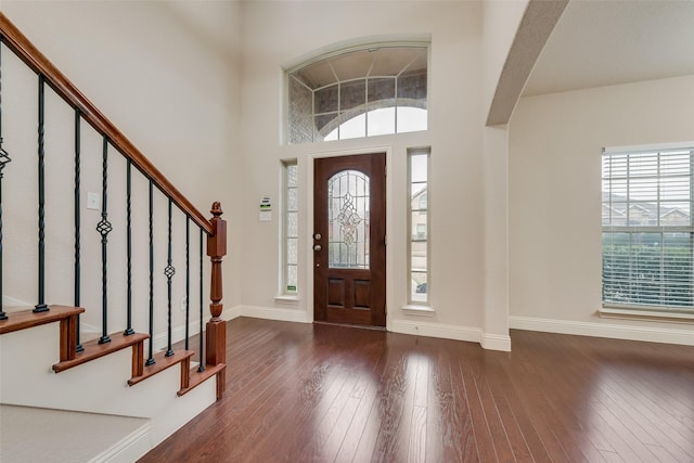 foyer entrance featuring a towering ceiling and dark hardwood / wood-style flooring