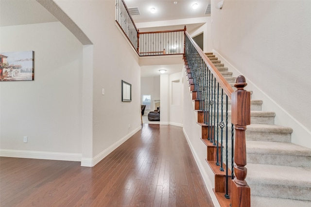 stairway featuring a high ceiling and hardwood / wood-style floors