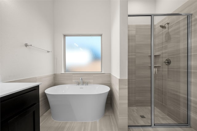 bathroom featuring vanity, tile walls, and separate shower and tub