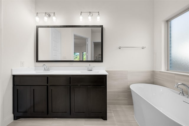 bathroom with vanity, tile walls, tile patterned floors, and a tub to relax in