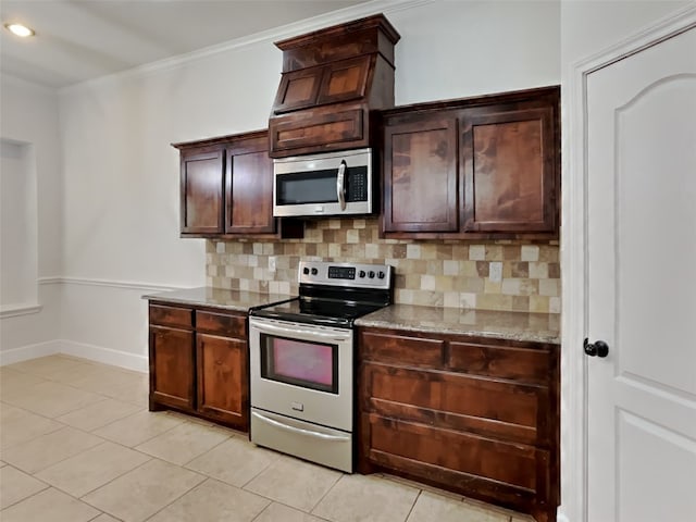 kitchen with tasteful backsplash, ornamental molding, stainless steel appliances, and light tile patterned floors