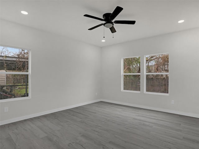 spare room with ceiling fan, light wood-type flooring, and a wealth of natural light