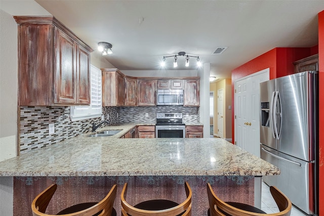 kitchen with sink, stainless steel appliances, kitchen peninsula, and a breakfast bar