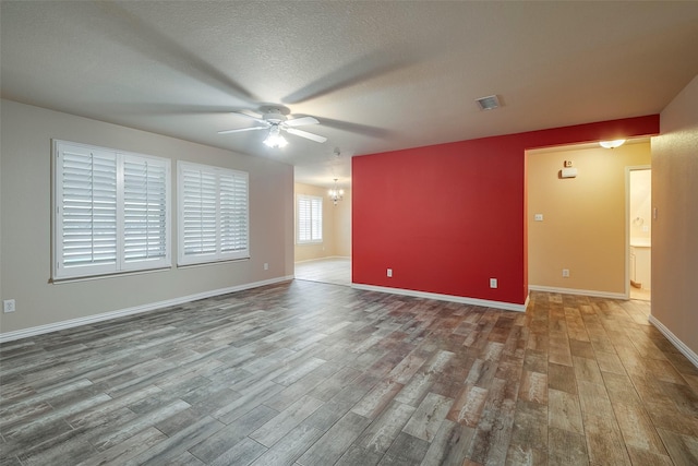 unfurnished room featuring ceiling fan with notable chandelier, hardwood / wood-style floors, and a textured ceiling