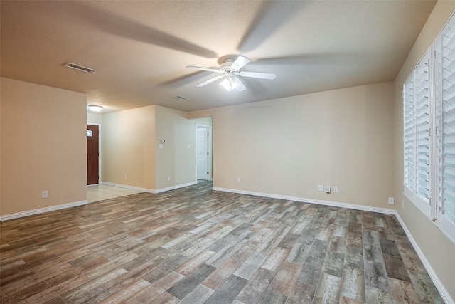 empty room with wood-type flooring, ceiling fan, and a textured ceiling