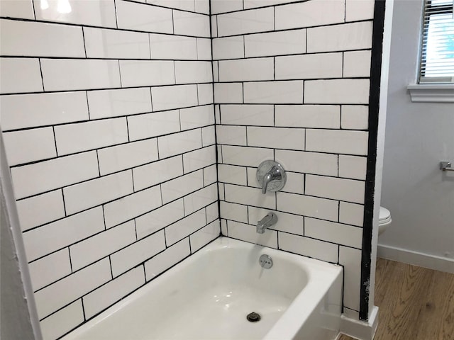 bathroom with tiled shower / bath, hardwood / wood-style flooring, and toilet