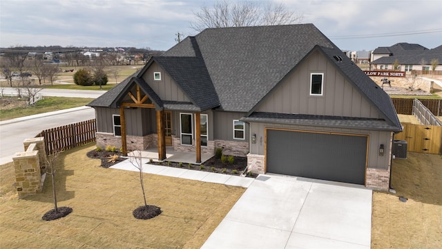 view of front of property featuring driveway, a shingled roof, board and batten siding, and fence