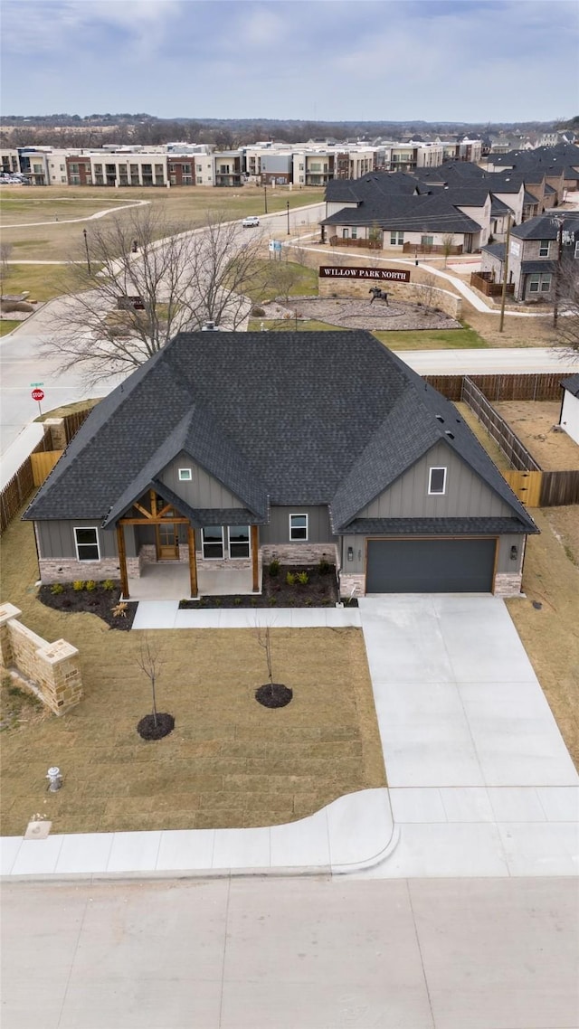 view of front of house featuring a shingled roof, a residential view, concrete driveway, and an attached garage