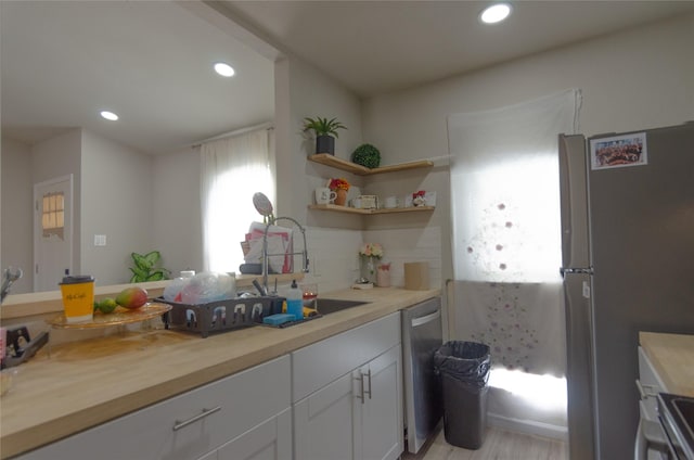 kitchen with white cabinetry, stainless steel appliances, wooden counters, and decorative backsplash