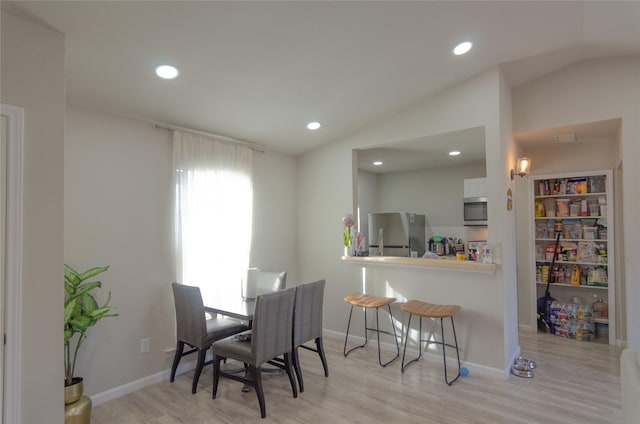 dining area featuring light hardwood / wood-style floors and vaulted ceiling