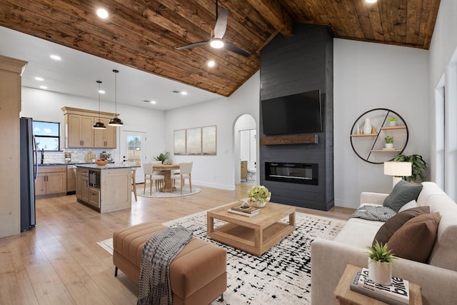 living room with wood ceiling, high vaulted ceiling, light wood-type flooring, a large fireplace, and beam ceiling