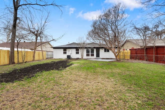 rear view of property with central AC unit and a lawn