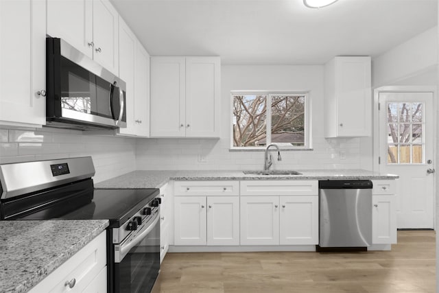 kitchen featuring light stone countertops, white cabinetry, appliances with stainless steel finishes, and sink