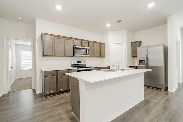 kitchen featuring hardwood / wood-style flooring, appliances with stainless steel finishes, sink, and a center island with sink