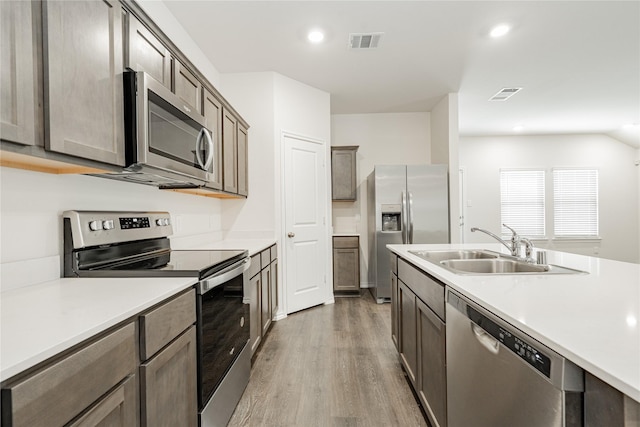 kitchen with appliances with stainless steel finishes, sink, and wood-type flooring