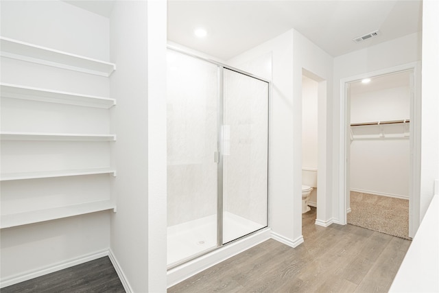 bathroom featuring wood-type flooring, an enclosed shower, and toilet