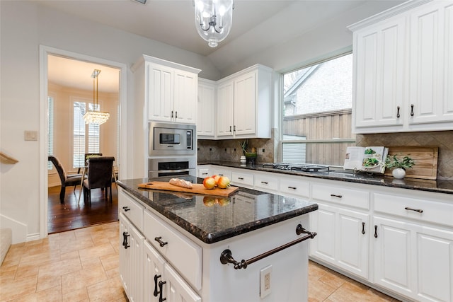 kitchen with a chandelier, white cabinetry, appliances with stainless steel finishes, a center island, and decorative light fixtures