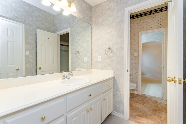 bathroom featuring vanity, toilet, and wallpapered walls