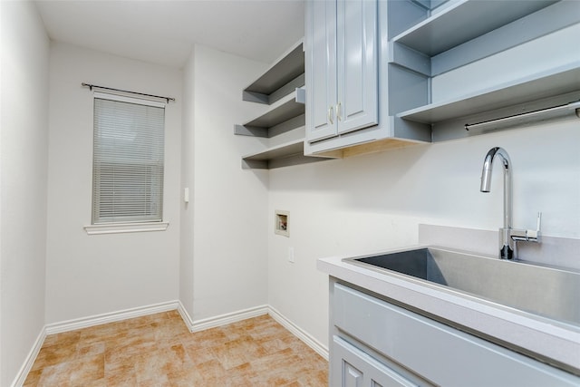 laundry area featuring hookup for a washing machine, cabinet space, a sink, and baseboards