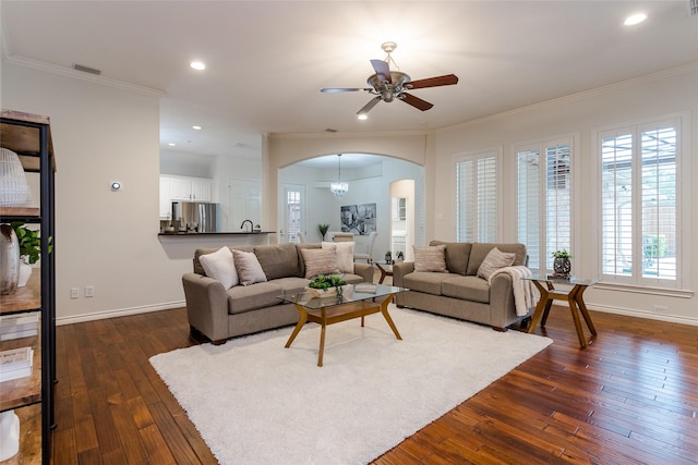 living room featuring arched walkways, dark wood-type flooring, visible vents, baseboards, and crown molding