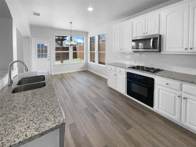 kitchen featuring sink, white cabinetry, light stone counters, hanging light fixtures, and black appliances