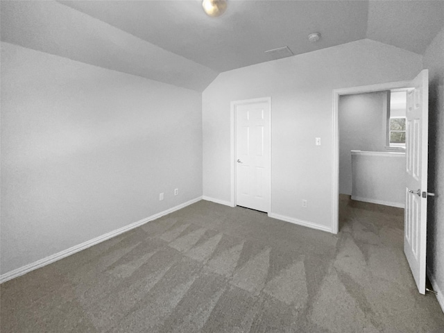 unfurnished bedroom with dark colored carpet and lofted ceiling