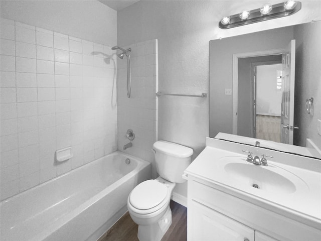 full bathroom featuring tiled shower / bath combo, vanity, hardwood / wood-style floors, and toilet