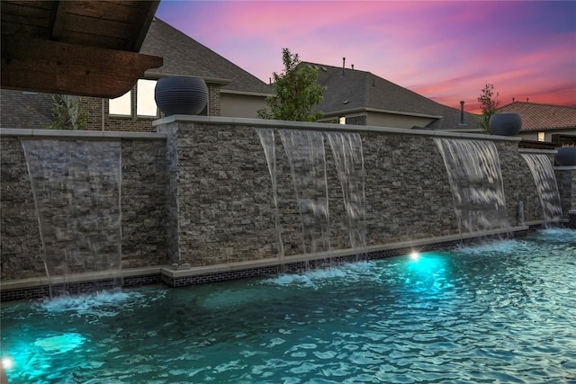 gate at dusk featuring pool water feature