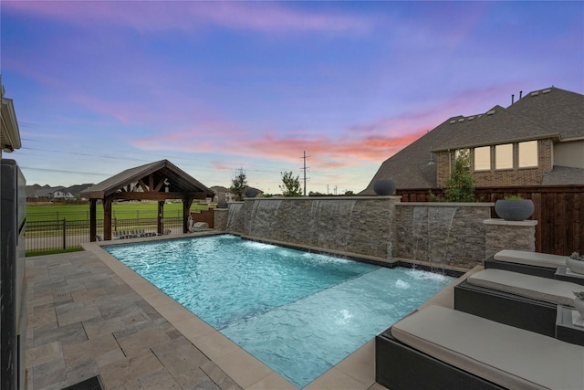 pool at dusk with a gazebo, pool water feature, and a patio