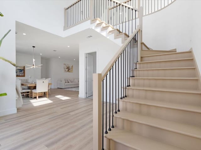 stairway with recessed lighting, ceiling fan, a high ceiling, and wood finished floors