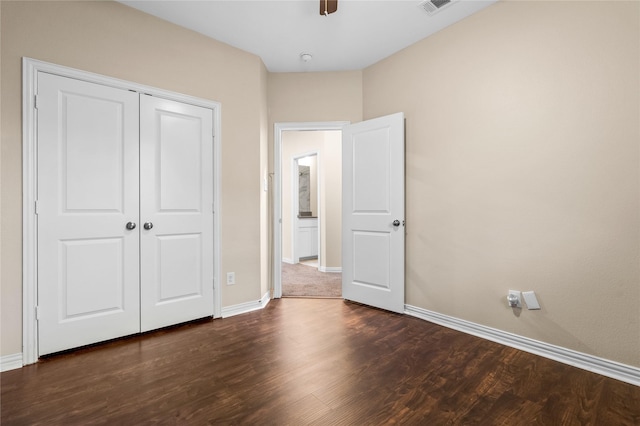 unfurnished bedroom featuring dark wood-type flooring, a closet, and ceiling fan