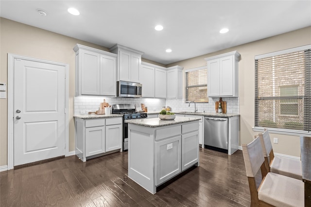 kitchen with dark wood-type flooring, sink, white cabinetry, a kitchen island, and stainless steel appliances