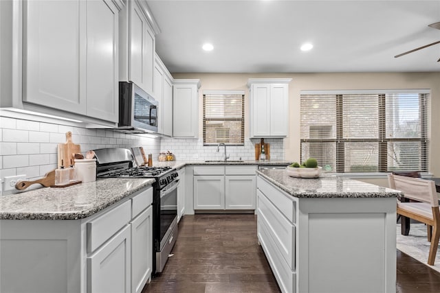 kitchen with stainless steel appliances, a center island, sink, and white cabinets