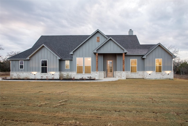 modern farmhouse style home featuring a front yard, a chimney, board and batten siding, and roof with shingles