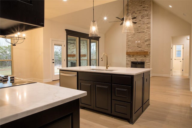 kitchen with dishwasher, light countertops, light wood-type flooring, a brick fireplace, and a sink