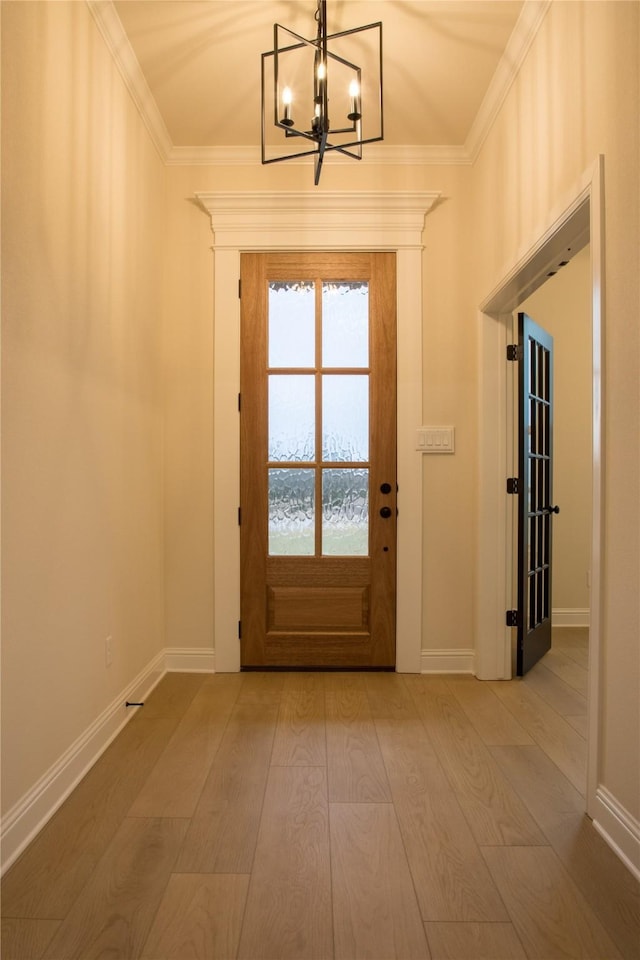 doorway featuring crown molding, a notable chandelier, baseboards, and wood finished floors