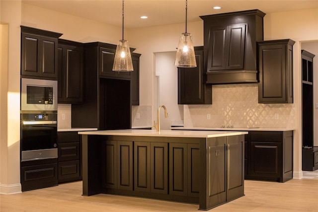 kitchen with a sink, light wood-style floors, light countertops, appliances with stainless steel finishes, and range hood